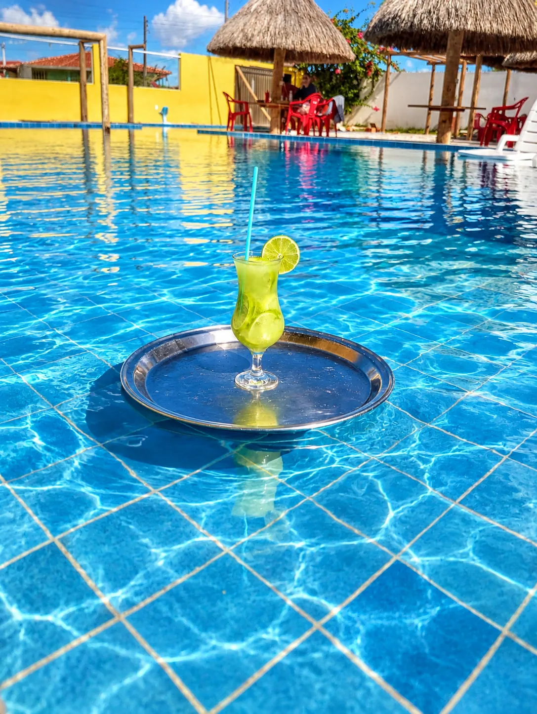 Drink servido em bandeja sobre a piscina