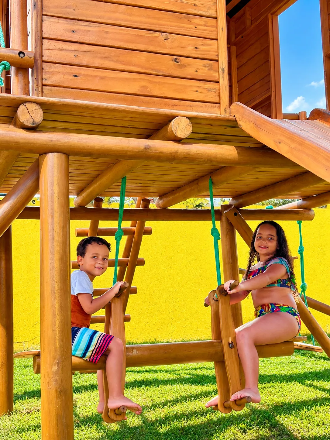 Crianças sorrindo nos balanços do parque infantil do hotel